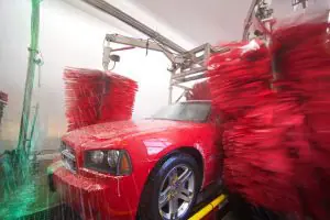 red car going through a flagstop car wash with red wipers and green soap