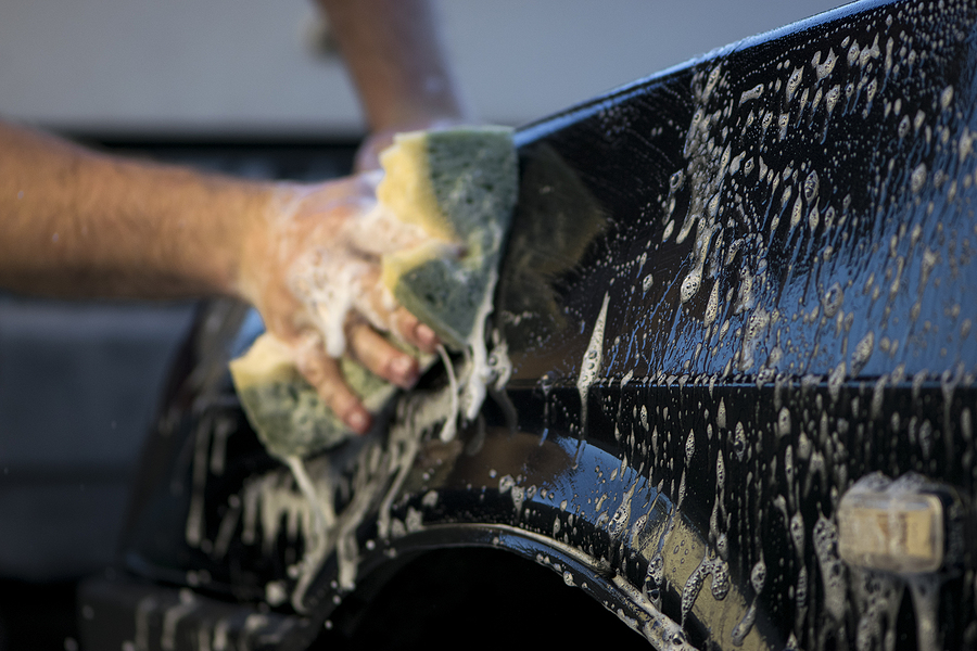 Washing the car with a sponge and soap.